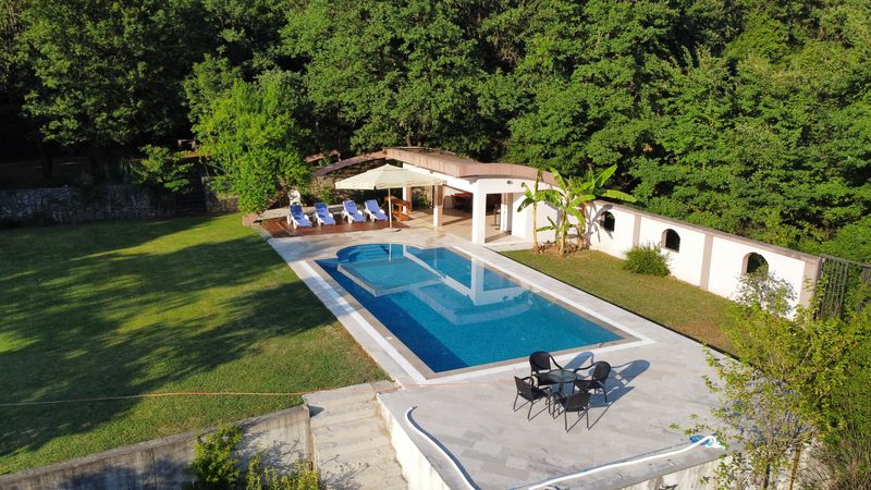 Bazen sa ležaljkama, suncobranom i baštenskim setom okružen šumom