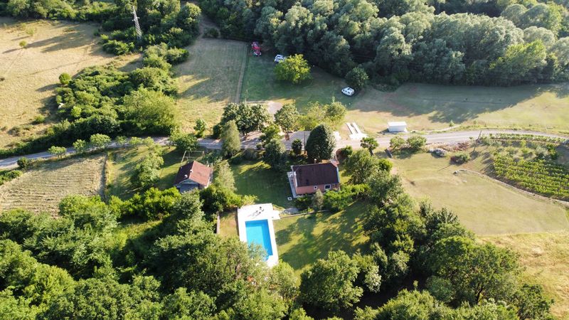 Vazdušni snimak imanja kampa sa kućama, bazenom i okolnim poljima