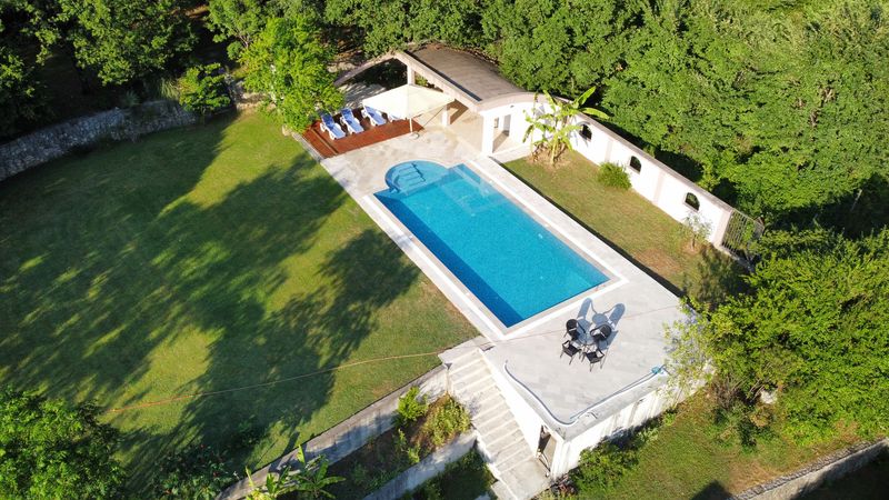 Vazdušni snimak izduženog bazena sa ležaljkama i baštenskim setom na travnjaku
